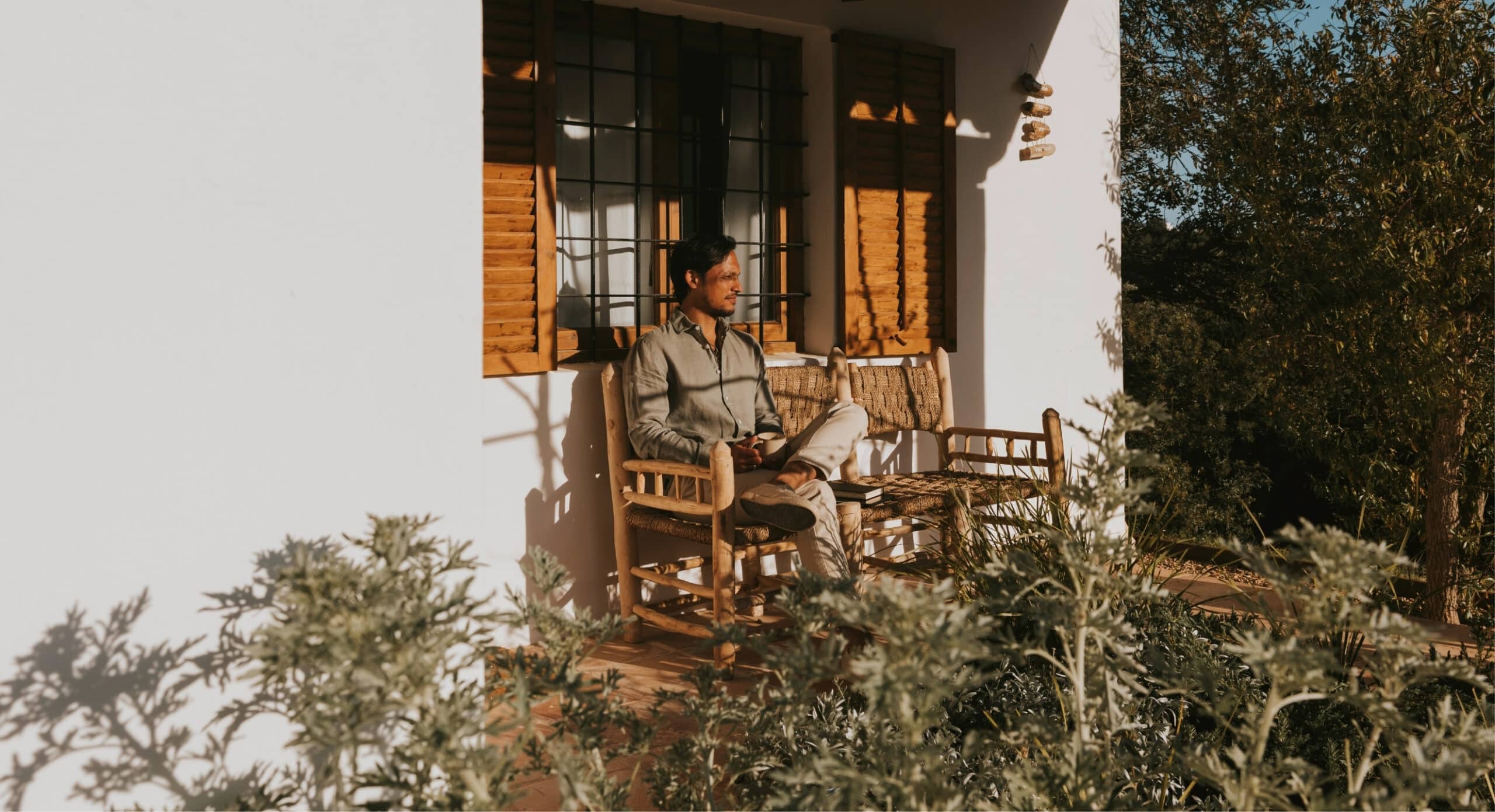 Architect Bjorn Kasandikromo zit in het avondlicht op het terras van een Ibiza finca met witgekalkte muren en houten luiken